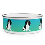 Cavalier King Charles Spaniel Enamel Bowl – Image description – White enamel bowl with a blue fading into green stripe with a Cavalier King Charles Spaniel sitting in the middle of the stripe. The dog has a black head and white body with his head slightly tilted. This dog is spaced out on the bowl and is visible in 2 ½ places in this image. The top of the bowl has a silver rim. 