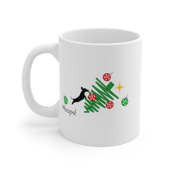 Tumbled Christmas Tree 11oz Mug - White mug with a picture of a line Christmas tree on it's side and a black silhouette dachshund jumping on the tree with several red and green ornaments falling off the tree. Whoops is written under the jumping dachshund.