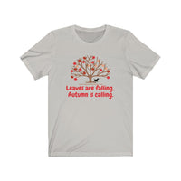 Image Description: Light Grey crew neck t-shirt. Orange and red maple leaves  on a brown tree trunk with a small black dog walking beside the tree trunk.  The www.DogsandTheirPaws.com url is under the tree.  The phrase, "Leaves are falling.  Autumn is calling." is below the image of the tree is in red.  